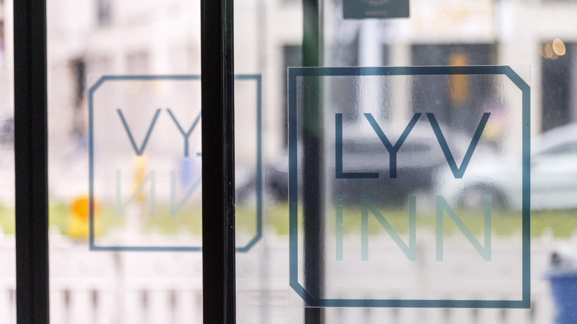 Das Logo des Lyvinn Hotels Frankfurt auf einer Glasscheibe, im Hintergrund verschwommen die Straße vor dem Hotel.
