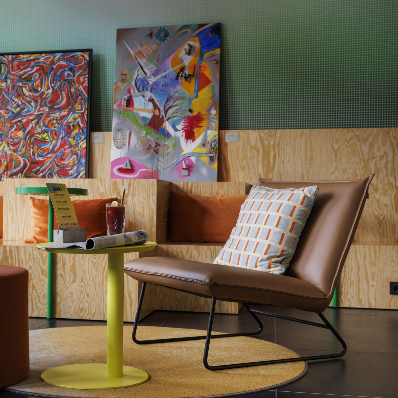 Moderne Hotellounge mit bunten Kunstwerken, gemütlichen Sitzmöbeln und warmen Farbtönen für entspanntes Ambiente.