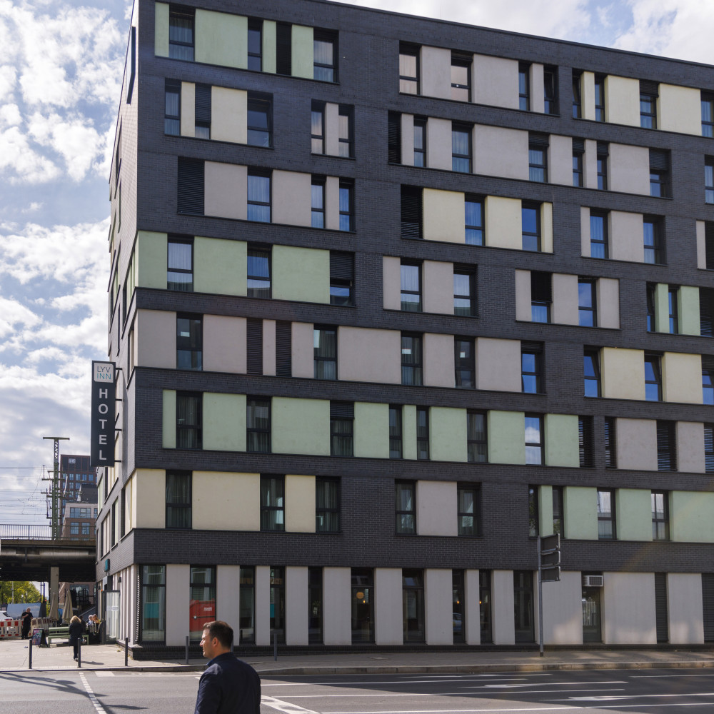 Mehrstöckiges, modernes Hotelgebäude mit bunten Fensterflächen an einer Straßenecke bei Tageslicht.