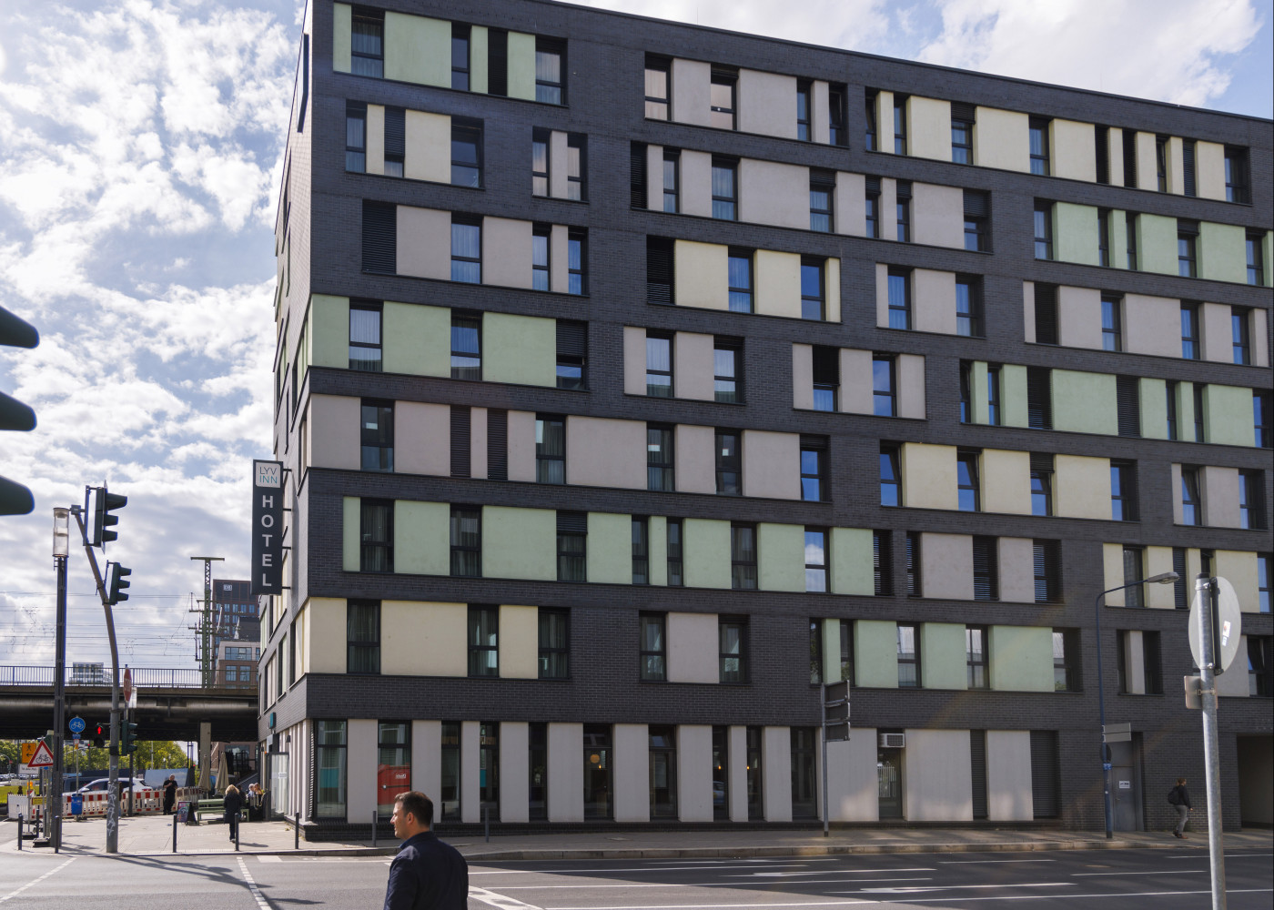  Mehrstöckiges, modernes Hotelgebäude mit bunten Fensterflächen an einer Straßenecke bei Tageslicht.