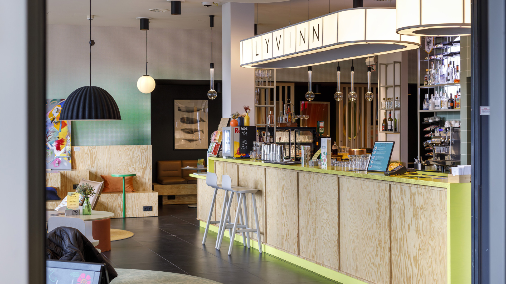 Moderne Hotelbar mit hellem Holzdesign, Neonakzenten und gemütlicher Sitzecke in der Lobby eines Designhotels.