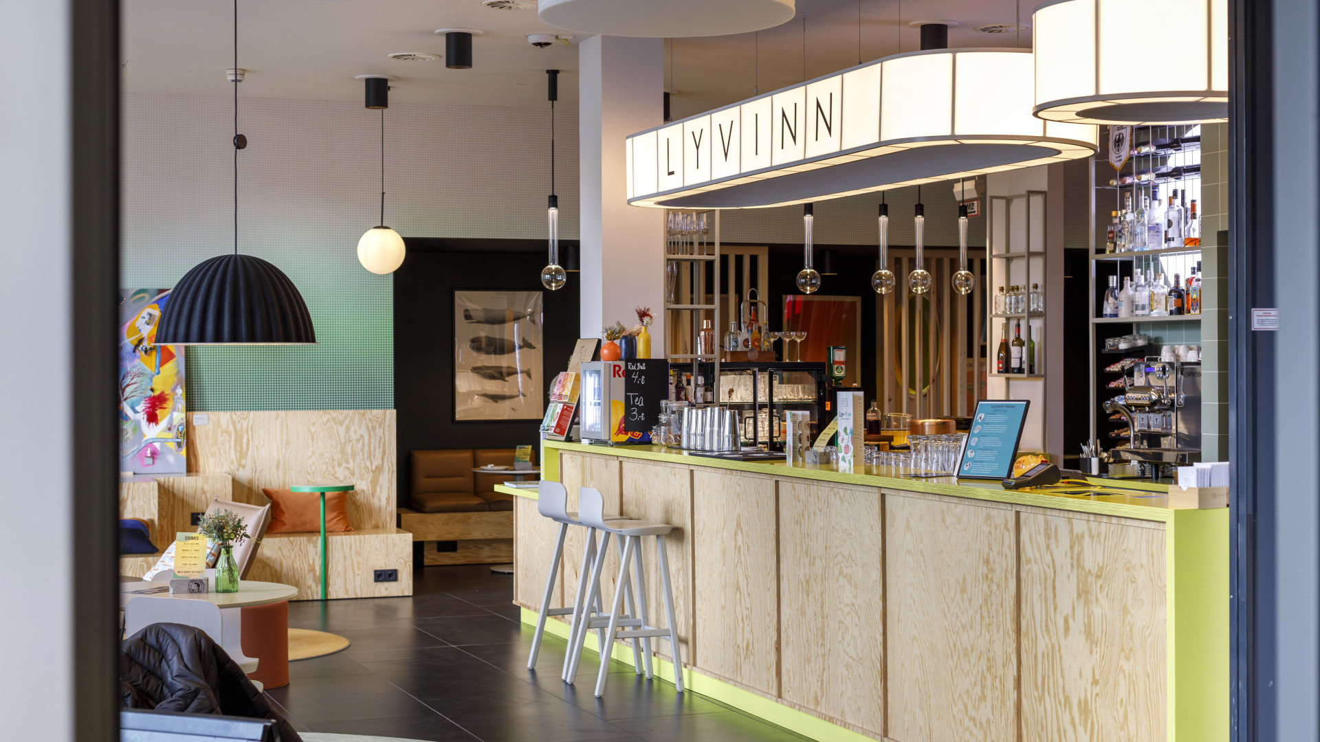 Moderne Hotelbar mit hellem Holzdesign, Neonakzenten und gemütlicher Sitzecke in der Lobby eines Designhotels.