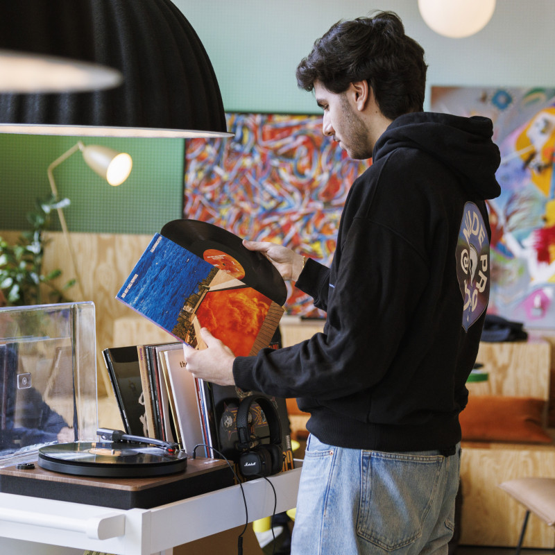 Gast steht mit einer Schallplatte in stylischer Hotellobby