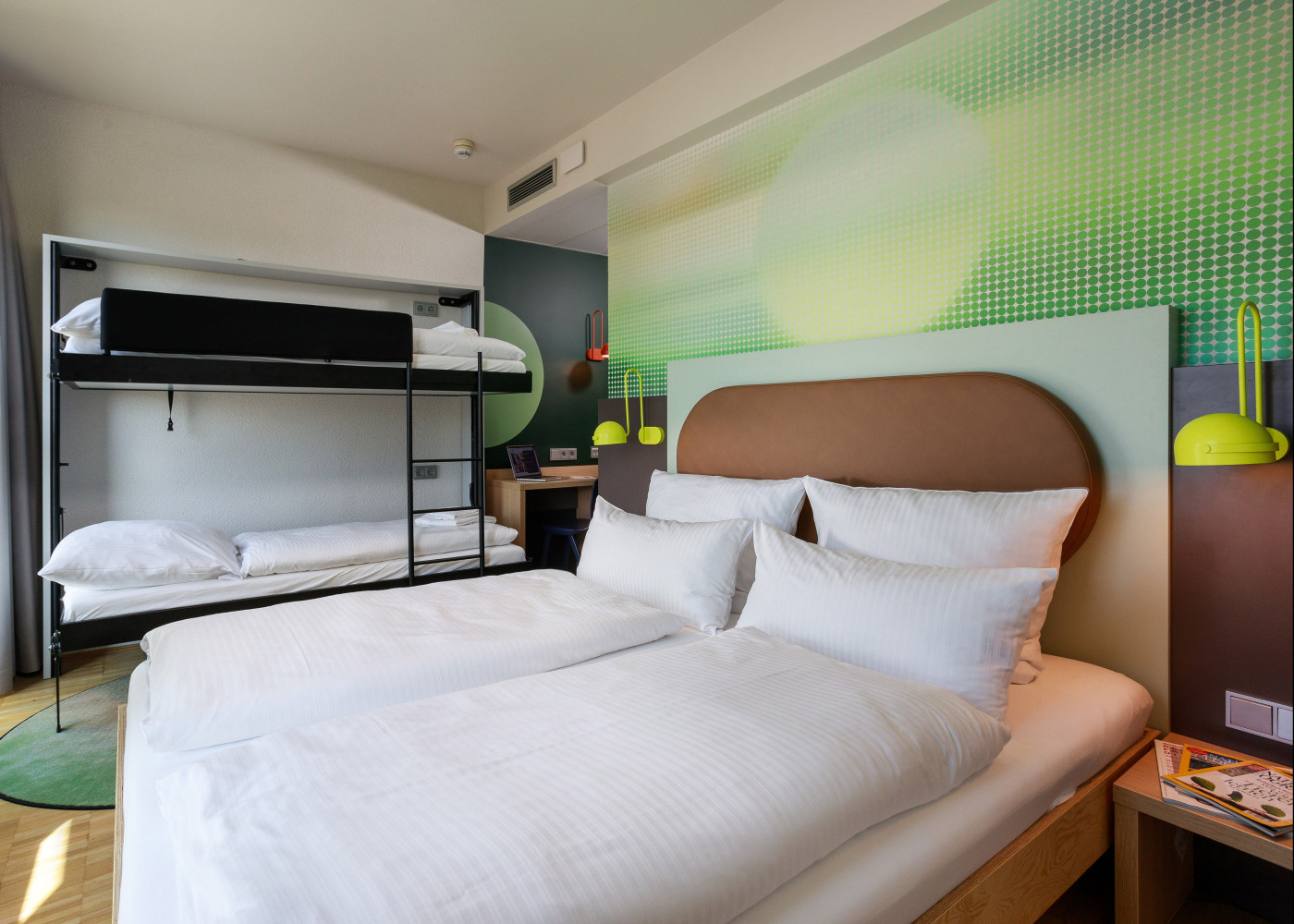 Hotelzimmer mit großem Doppelbett, Etagenbett und bunter Wandgestaltung, ideal für Familien oder Gruppen.