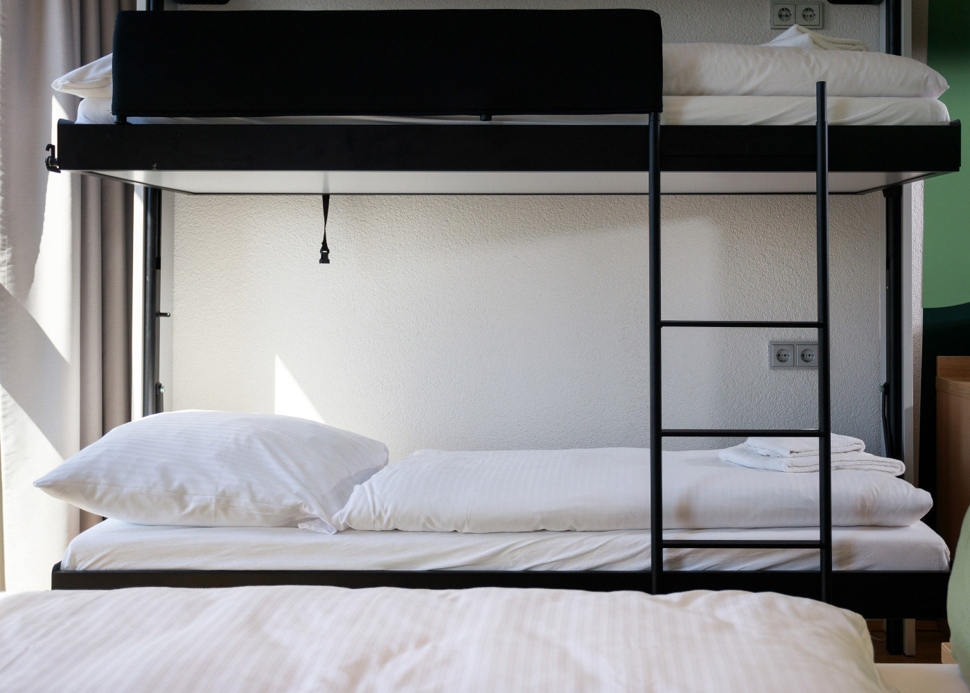 Modernes Etagenbett mit weißer Bettwäsche und Leiter, ideal für Familien oder Gruppen im Hotelzimmer.