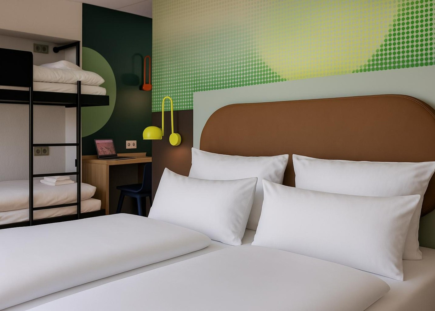 Ein Ausschnitt des Doppelbetts im Mehrbettzimmer, mit den Stockbetten im Hintergrund.